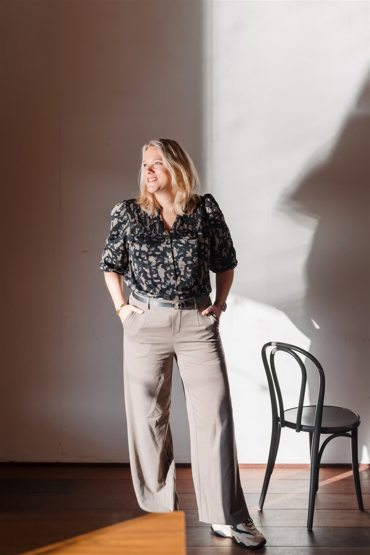 Vrouw staat naast stoel en kijkt weg van de camera